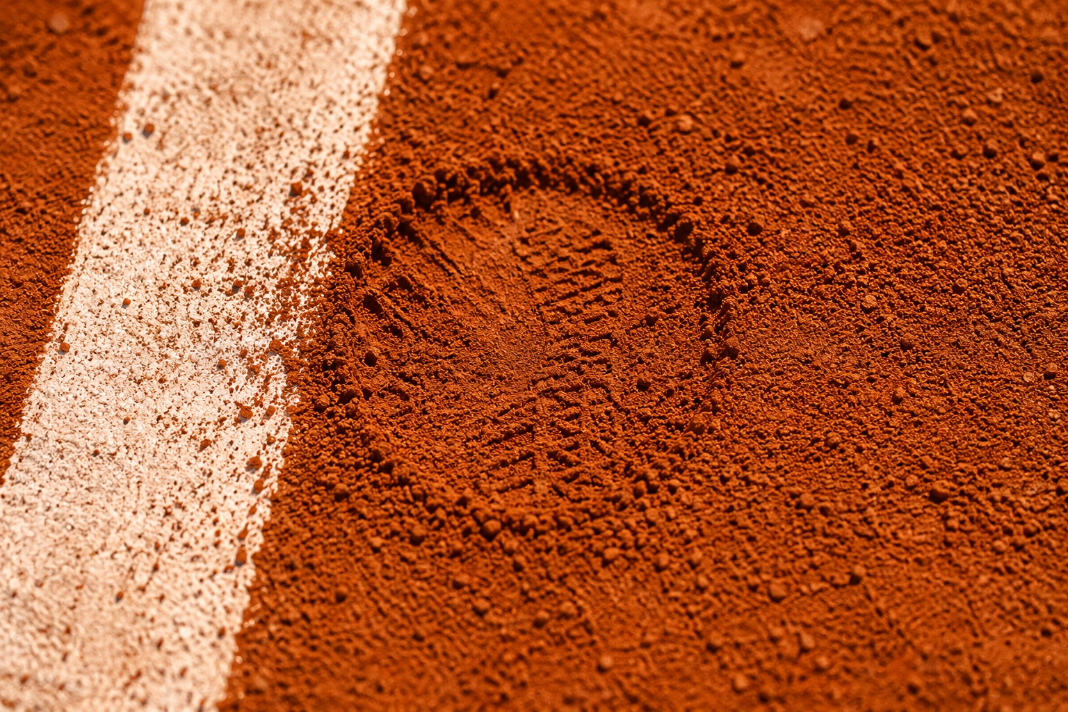 Close-up of red clay court texture with a white line